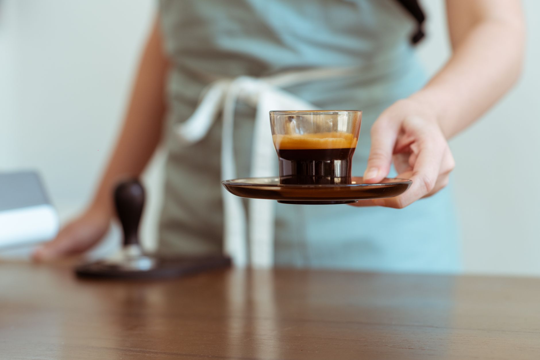 barista stirring espresso crema glass cup